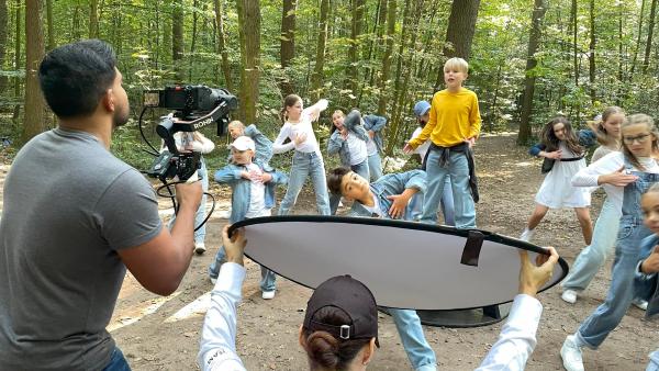 Performen mit anderen Kindern in einem Waldstück