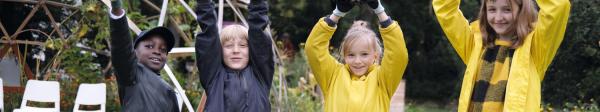 Vier Kinder im Garten mit Pflanzen in der Hand